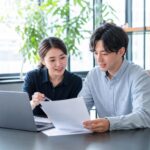 한국의 공연기획 사무실에서 E-6 체류 연장 자료를 검토하는 실무자와 외국인 예술인