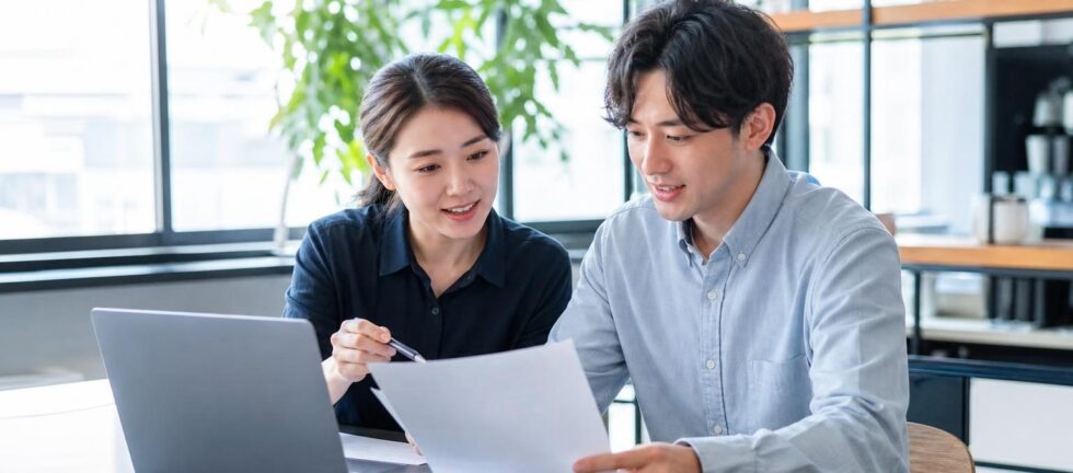 한국의 공연기획 사무실에서 E-6 체류 연장 자료를 검토하는 실무자와 외국인 예술인